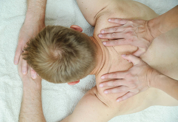 健康マッサージ療法。男の背中をマッサージしている女性の手. - 写真・画像