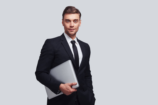 businessman in suit holding laptop in studio and looking at camera  - Foto, immagini