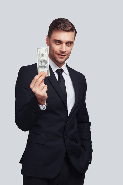 uitvoerend zakenman glimlachend en het aanhouden van geld in de studio  - Foto, afbeelding
