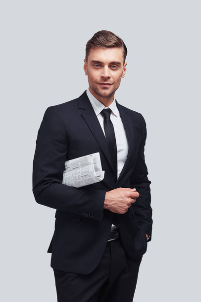 Confident businessman in suit looking at camera and holding newspaper  - Foto, Imagen