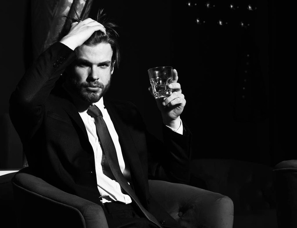 bearded man, businessman holding glass of whiskey in red chair - 写真・画像