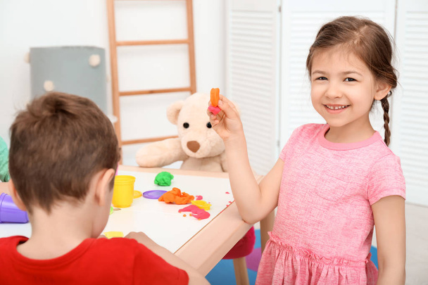 Cute little children using play dough at table indoors - Photo, image