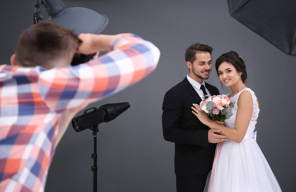 Professional photographer taking photo of wedding couple in studio - Фото, изображение