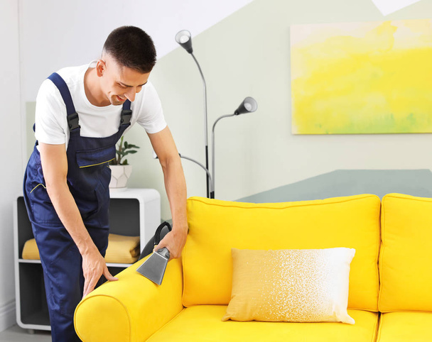Dry cleaning worker removing dirt from sofa indoors - Fotoğraf, Görsel