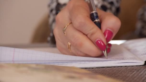 A woman writes handwritten text in a notebook - Filmati, video