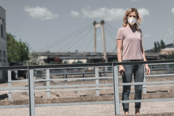 woman in protective mask standing on bridge, air pollution concept - Fotó, kép