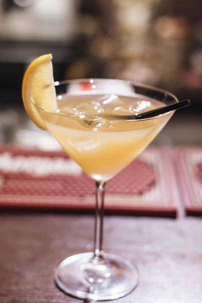 вкусный коктейль с кубиками льда, лимоном и соломой в баре
  - Фото, изображение