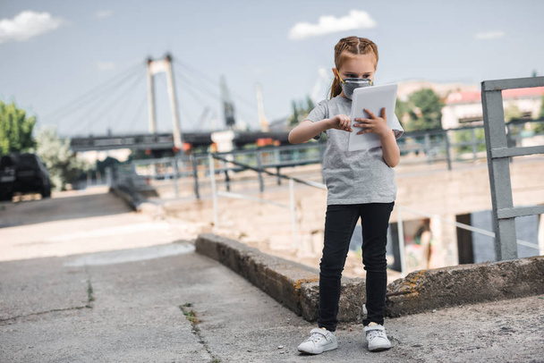 niño en máscara protectora usando tableta, concepto de contaminación del aire
 - Foto, Imagen