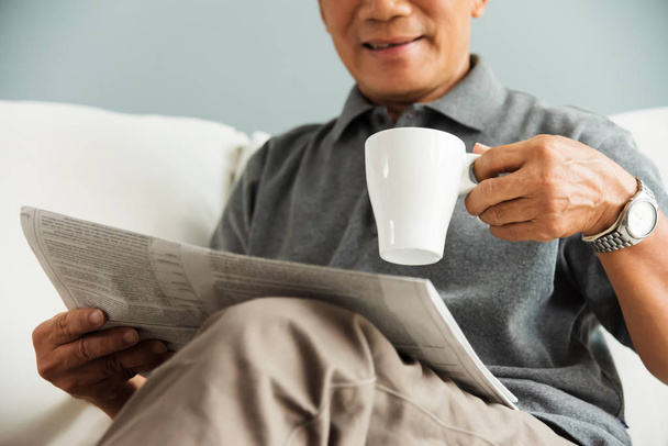 Happy Asian senior man smiling and drinking hot coffee while reading newspaper at his house. Relaxed, Free time, Smiling, Retirement. - Foto, Bild