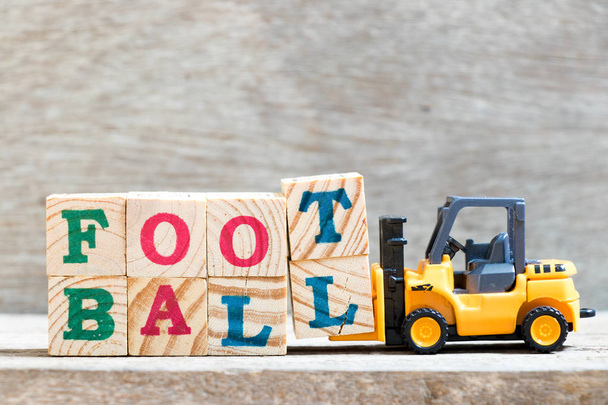Spielzeug Gabelstapler halten Buchstabe Block t, l zu vervollständigen Wort Fußball auf Holz Hintergrund - Foto, Bild