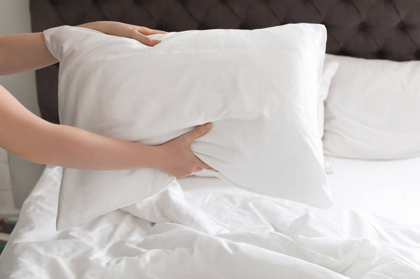 Young woman holding white pillow over bed, closeup - 写真・画像