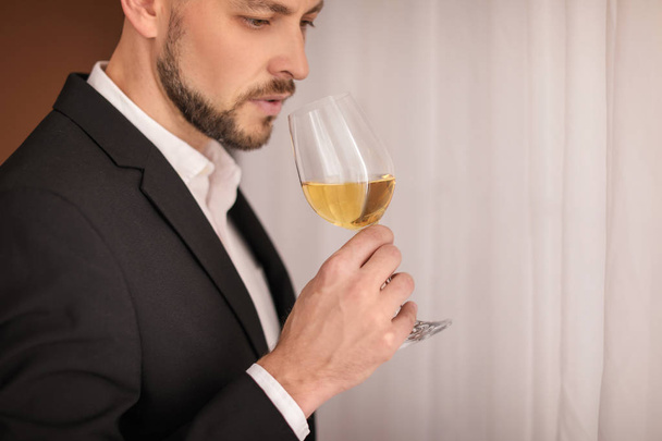 Young man with glass of wine indoors - Valokuva, kuva