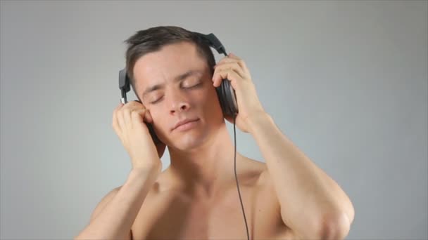 attraktiver glücklicher Kerl hört Musik über Kopfhörer. - Filmmaterial, Video
