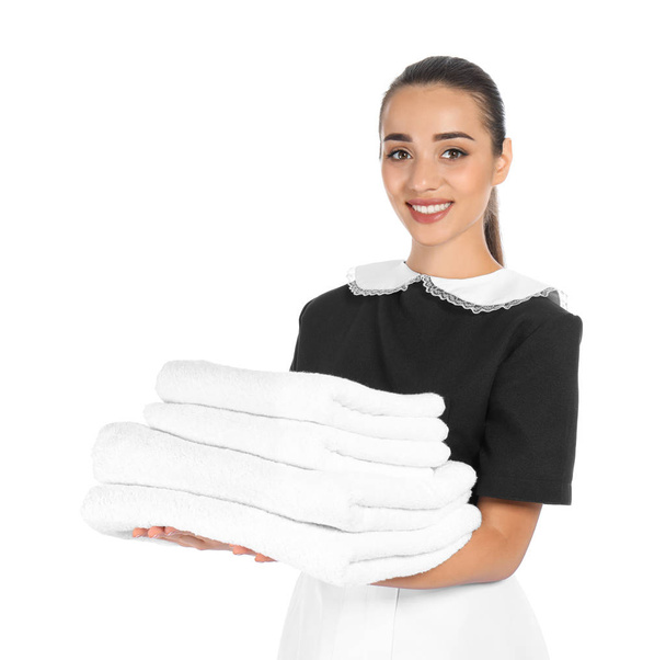 Young chambermaid with stack of clean towels on white background - Fotoğraf, Görsel