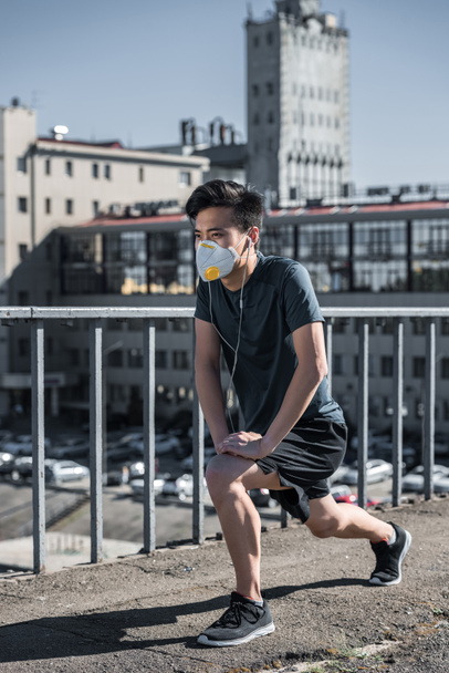 atlético asiático adolescente estiramiento en protección máscara en puente, aire contaminación concepto
 - Foto, Imagen