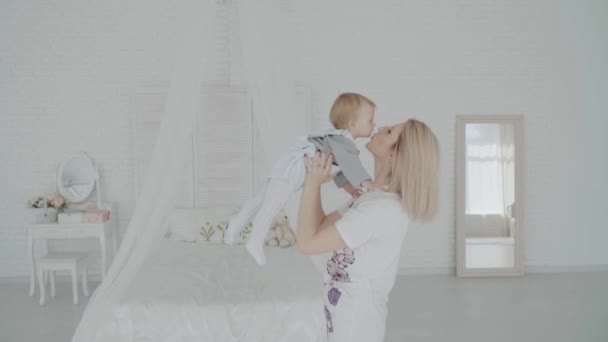 Mother swinging her beautiful daughter in the room. Happy family. Slow motion - Záběry, video