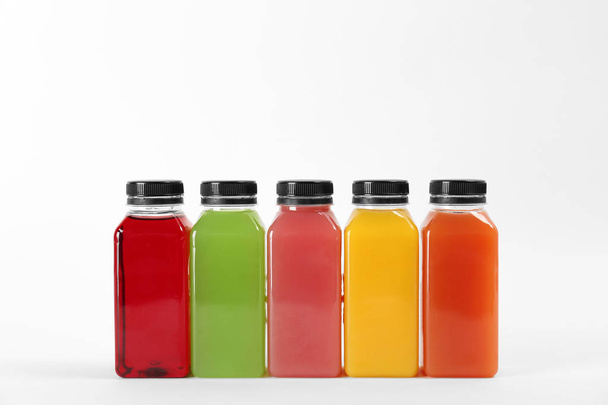 Bottles with delicious colorful juices on white background - 写真・画像