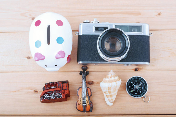 Концепция путешествия с ретро камерой, компасом, растением, копилкой и другой миниатюрой на деревянном столе
 - Фото, изображение