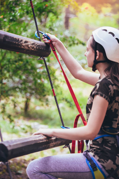school meisje genieten van activiteit in het avonturenpark klimmen - Foto, afbeelding