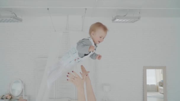 Mother swinging her beautiful daughter in the room. Happy family. Slow motion - Felvétel, videó