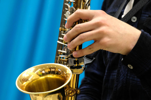 Primer plano de la mano masculina de un músico tocando en un saxofón dorado. Concepto para noticias musicales
. - Foto, imagen