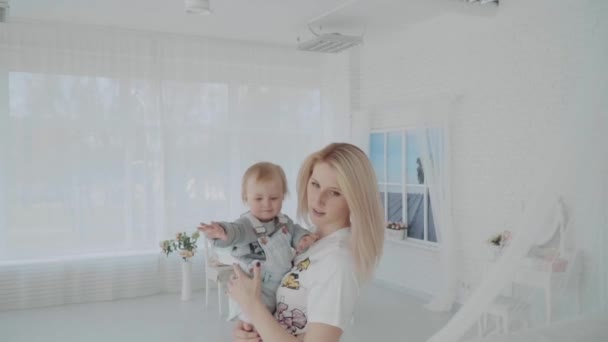 Mother swinging her beautiful daughter in the room. Happy family. Slow motion - Video, Çekim