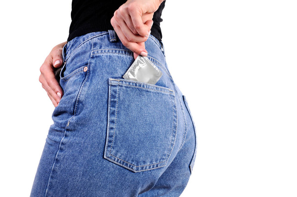 Condoms in package in back jeans pocket. Woman in jeans putting a condom a pocket.  - Fotoğraf, Görsel