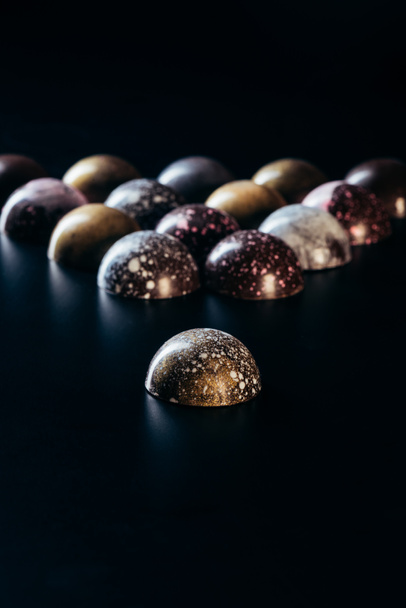 closeup view of pile of chocolate candies on black background  - Fotó, kép