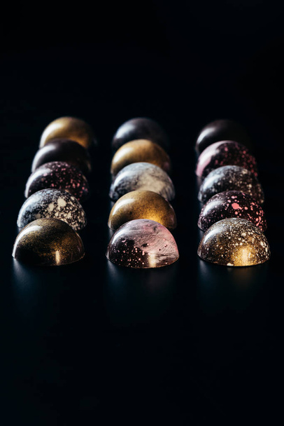 different chocolate candies placed in rows on black background  - Foto, Bild