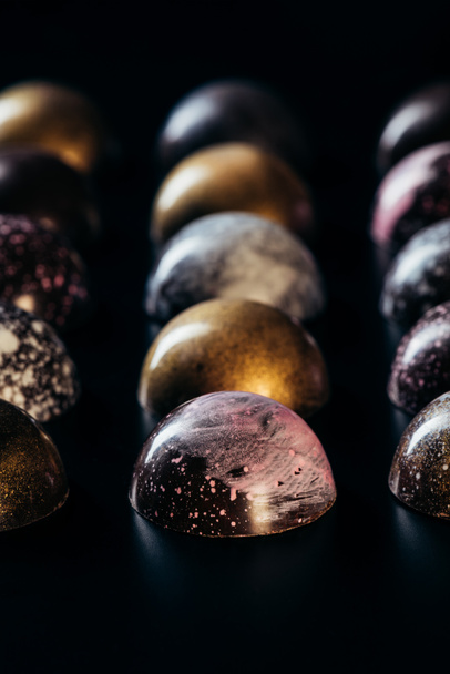 closeup view of different chocolate candies placed in rows on black background  - Valokuva, kuva