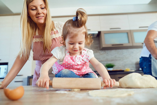 A child with his mother prepares the dough for cookies. - Fotó, kép
