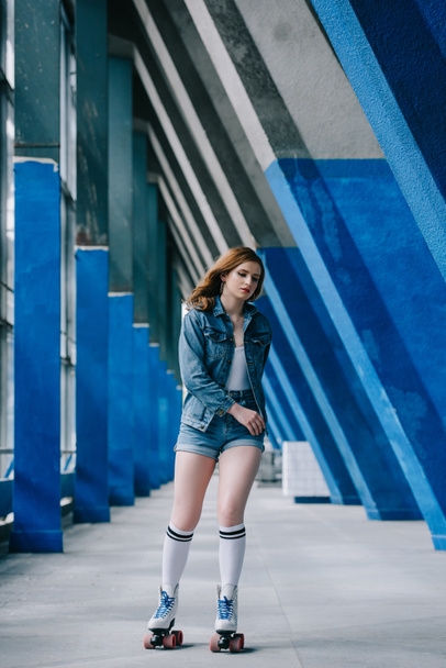 fashionable young woman in denim clothing and high socks roller skating alone - Foto, Imagen