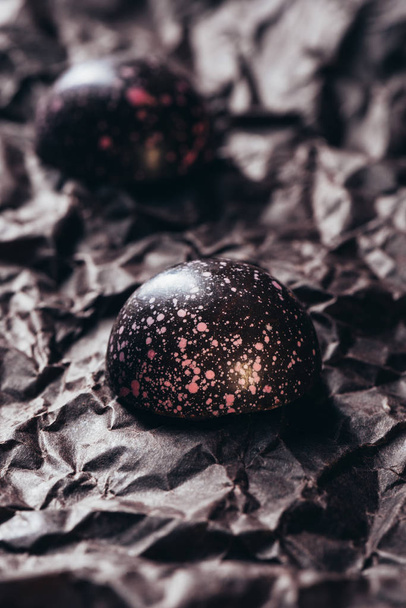 vue rapprochée de deux bonbons au chocolat avec éclaboussures roses sur papier froissé
 - Photo, image