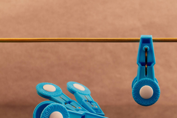 Clothespin of blue plastic hanging on a wooden stick, next to the left are a few blue clothes pegs. - Photo, Image