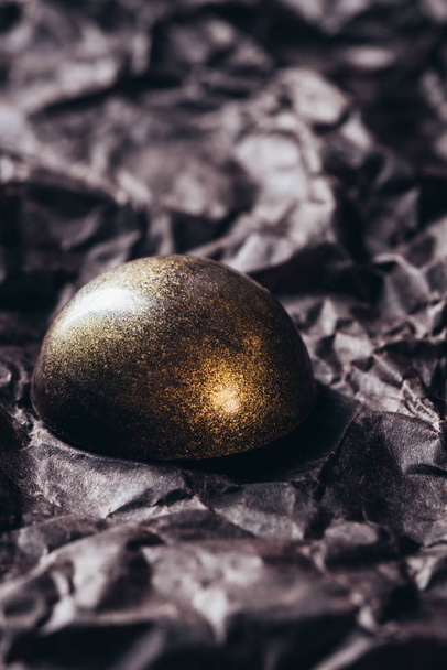 closeup view of chocolate candy with golden splashes on crumpled paper  - Valokuva, kuva