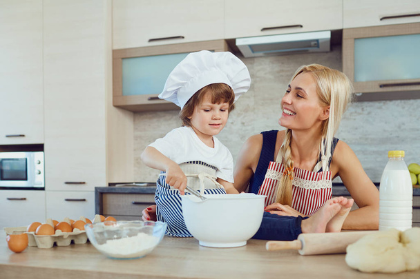 Moeder en zoon bakken taarten in de keuken - Foto, afbeelding