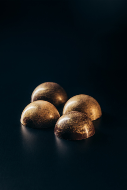 closeup image of chocolate candies with golden splashes on black background  - Valokuva, kuva