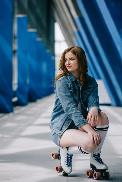 young stylish woman in denim clothes, high socks and retro roller skates looking away - Foto, afbeelding