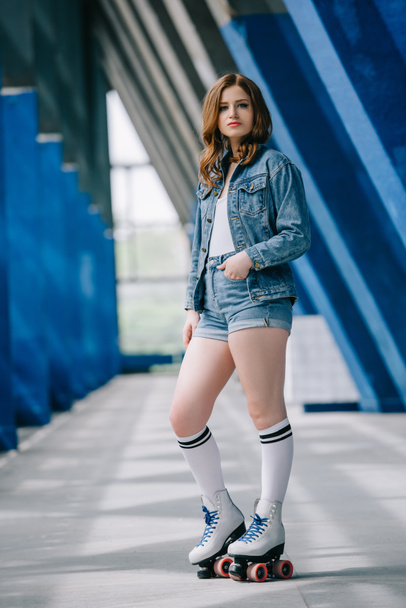 side view of stylish woman in denim clothing, high socks and retro roller skates - Fotó, kép