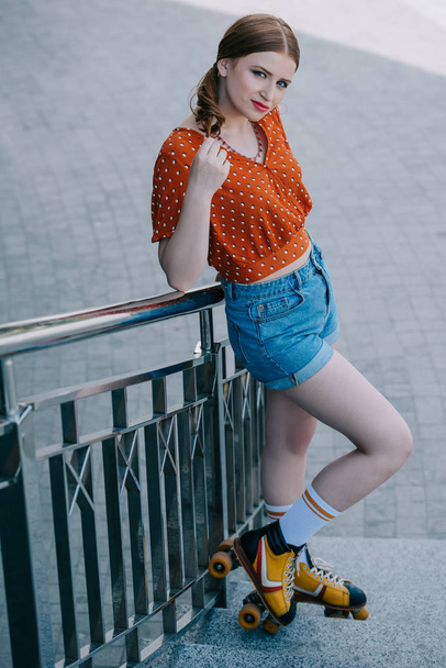 stylish girl in roller skates standing on stairs and looking at camera - 写真・画像