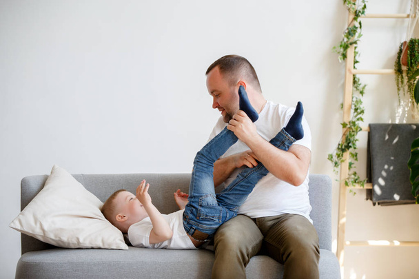 Photo of young father with son playing on sofa - Foto, afbeelding