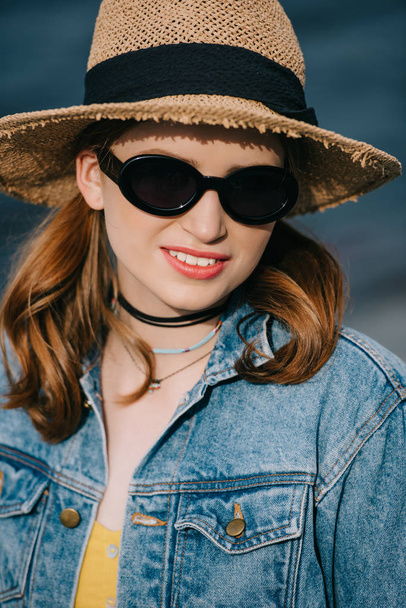 portrait of beautiful stylish girl in sunglasses and hat smiling at camera - Foto, immagini