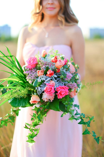 Jolie femme debout avec bouquet de fleurs portant une robe rose
. - Photo, image