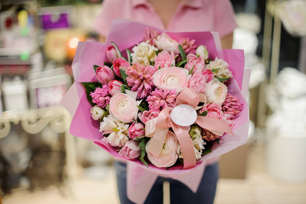 Girl in pink shirt holding in her hands a beautiful big bouquet of pink tender spring flowers - 写真・画像