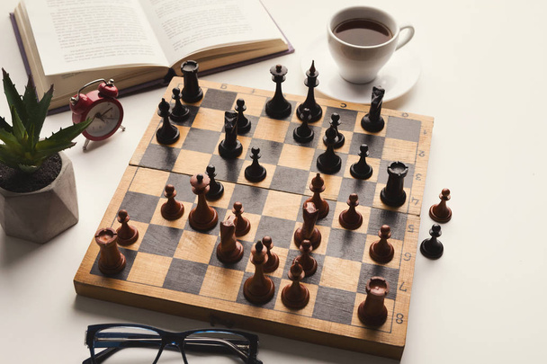 Wooden desk with chess play, book and coffee cup - Foto, afbeelding