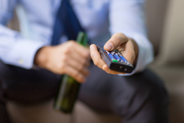 close up of man with tv remote drinking beer - Foto, Bild