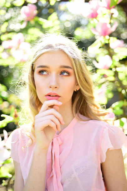 Thoughtful blond girl posing on natural background. Dreamy young lady in pink blouse walking in blooming garden, spring freshness concept. - Fotó, kép