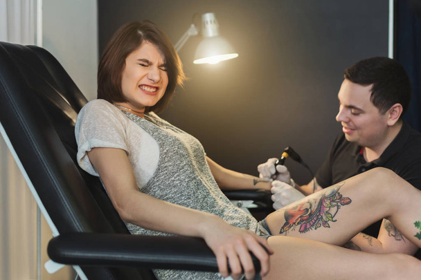 Doloroso proceso de tatuaje corporal, maestro trabajando en el estudio
 - Foto, imagen
