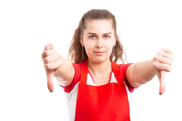 Молода жінка працівник супермаркету показує великі пальці вниз як концепцію відмови від жесту відторгнення ізольовані на білому тлі
 - Фото, зображення