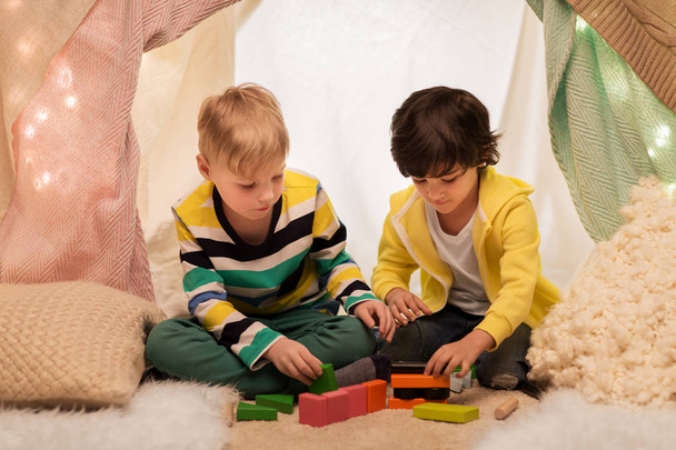 boys playing toy blocks in kids tent at home - Foto, afbeelding